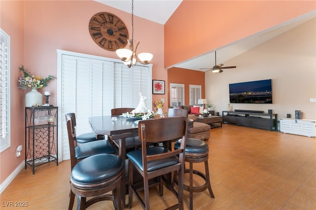 dining area featuring light wood-style flooring, baseboards, high vaulted ceiling, and ceiling fan