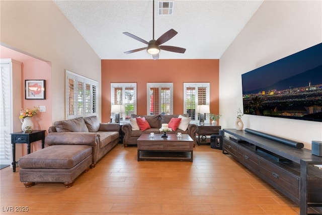 living room with high vaulted ceiling, a ceiling fan, visible vents, and light wood-type flooring