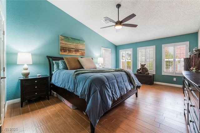 bedroom with baseboards, lofted ceiling, a textured ceiling, and wood finished floors