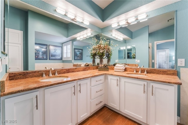 bathroom featuring double vanity, wood finished floors, visible vents, and a sink