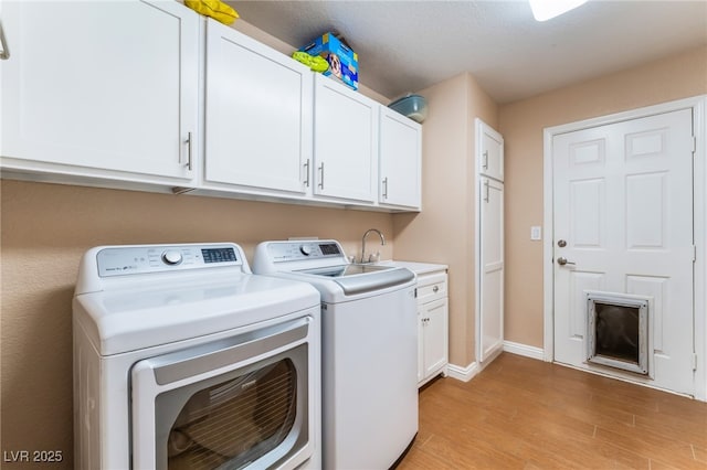 laundry room featuring baseboards, light wood finished floors, cabinet space, a sink, and washer and clothes dryer