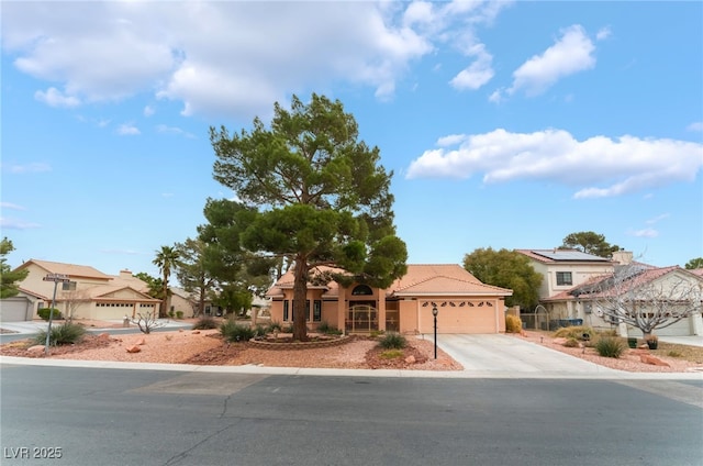 mediterranean / spanish-style home with an attached garage, stucco siding, concrete driveway, a tile roof, and a residential view