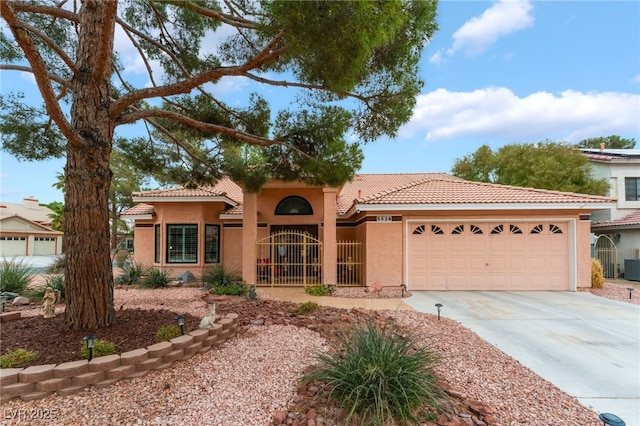 mediterranean / spanish house with a tiled roof, stucco siding, an attached garage, and driveway