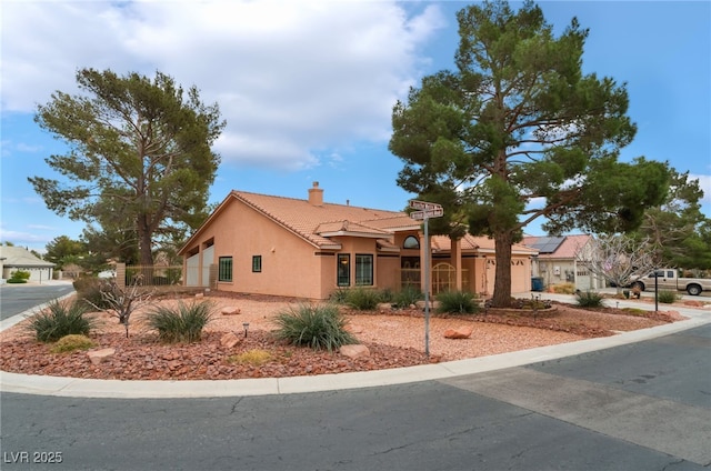 view of front of property with stucco siding, a tiled roof, and a chimney