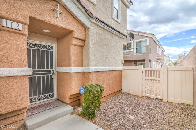 property entrance with stucco siding and fence