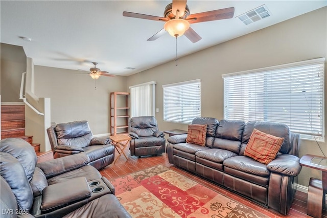 living room with visible vents, baseboards, stairway, wood finished floors, and a ceiling fan