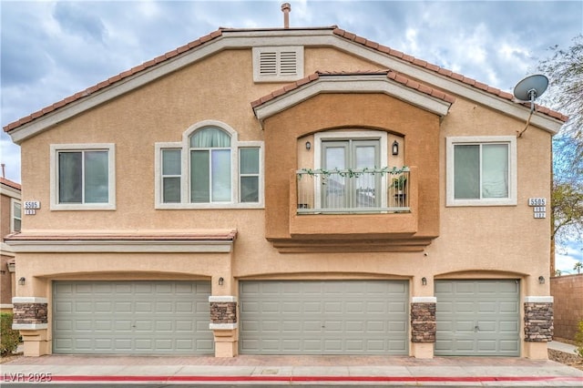 multi unit property with stucco siding, stone siding, and a garage