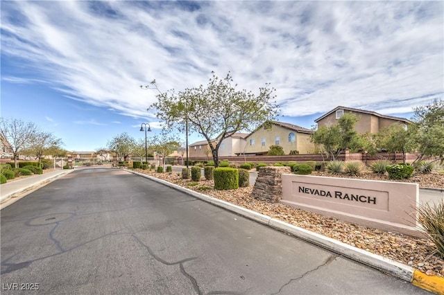 view of street featuring a gated entry, a residential view, and curbs