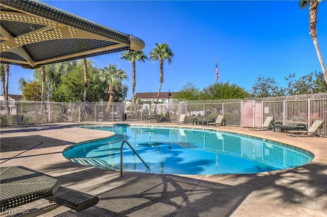 community pool with a patio area and fence