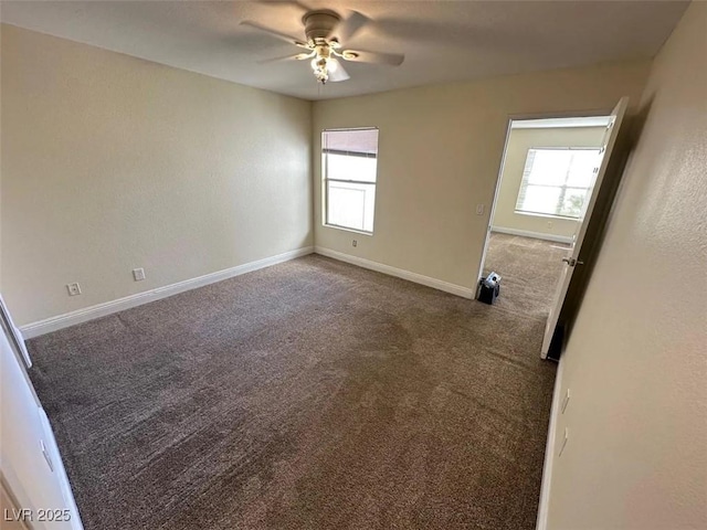 carpeted spare room with a healthy amount of sunlight, baseboards, and ceiling fan