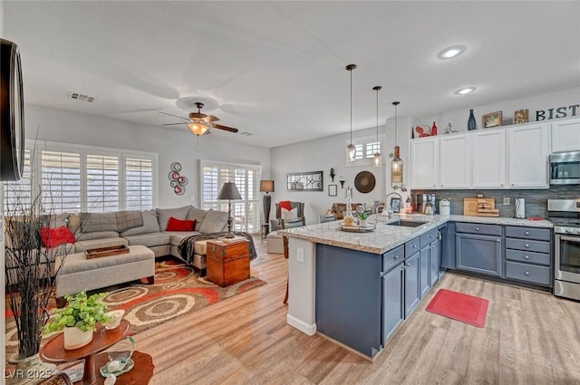 kitchen featuring visible vents, a peninsula, a sink, appliances with stainless steel finishes, and open floor plan