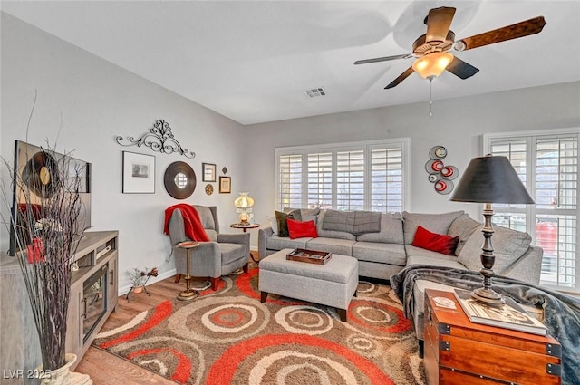 living room featuring baseboards, wood finished floors, visible vents, and ceiling fan