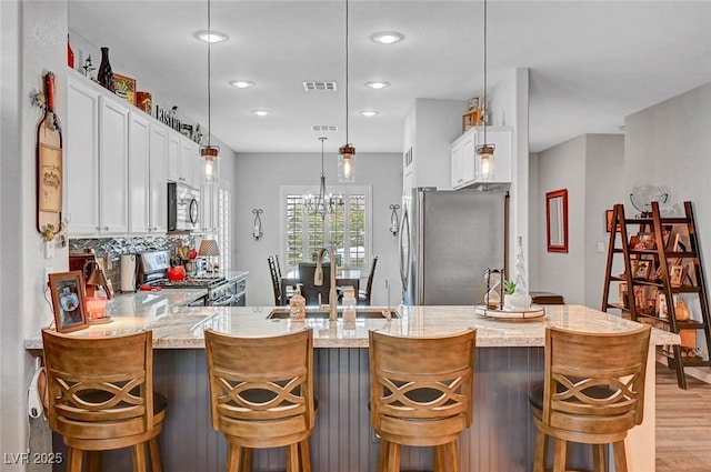 kitchen with a sink, white cabinets, light wood finished floors, and stainless steel appliances