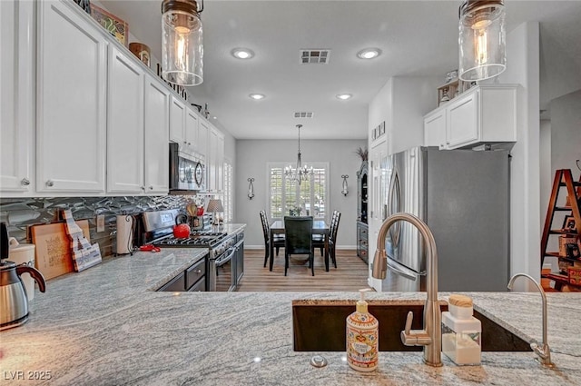 kitchen featuring light wood finished floors, visible vents, light stone countertops, stainless steel appliances, and white cabinetry