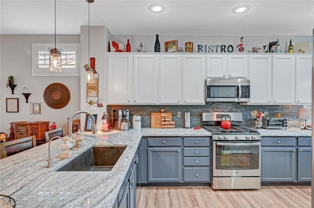 kitchen featuring a sink, stainless steel appliances, backsplash, and gray cabinets