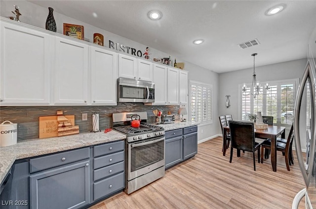 kitchen with white cabinetry, tasteful backsplash, gray cabinets, and appliances with stainless steel finishes