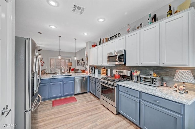 kitchen with visible vents, a sink, tasteful backsplash, light wood-style floors, and appliances with stainless steel finishes