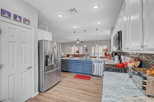 kitchen with light wood finished floors, visible vents, a peninsula, white cabinets, and stainless steel appliances