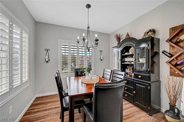 dining space with baseboards, a chandelier, and light wood finished floors