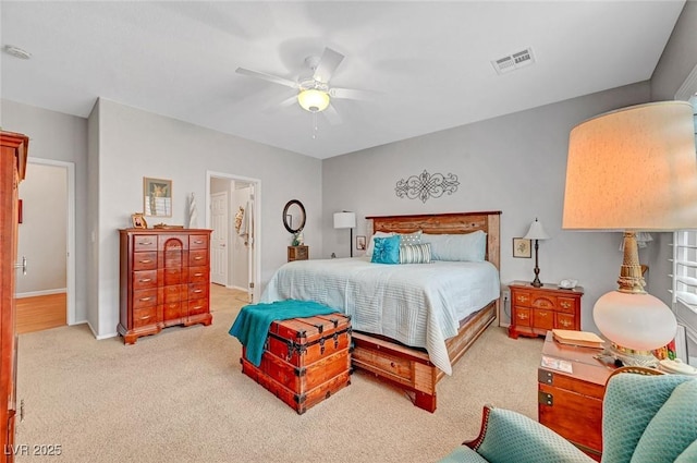 bedroom featuring a ceiling fan, visible vents, carpet floors, baseboards, and ensuite bath