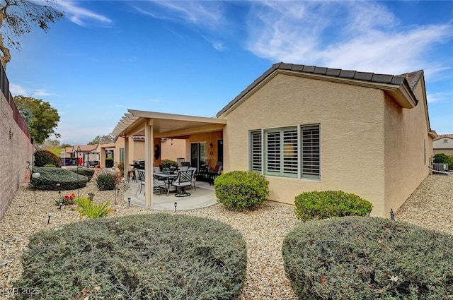 rear view of house with a patio area, central air condition unit, and stucco siding