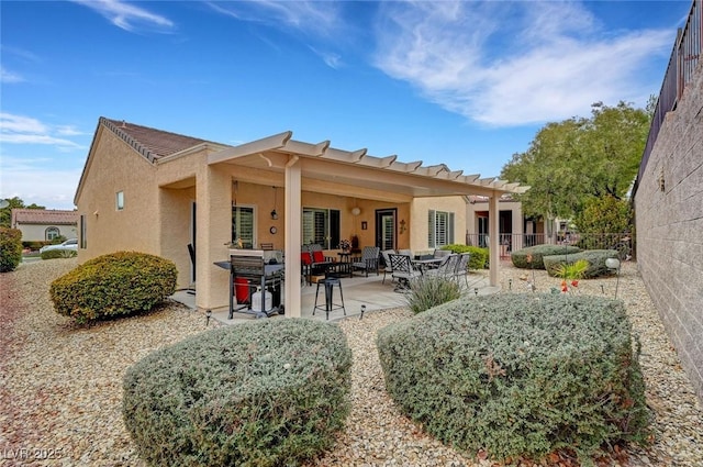 rear view of property featuring stucco siding, a patio, and fence