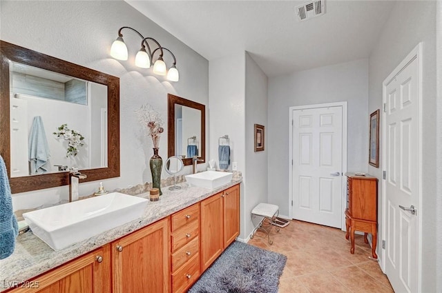 full bathroom with tile patterned flooring, visible vents, double vanity, and a sink