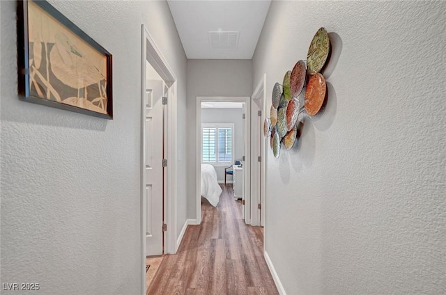 hall featuring wood finished floors and a textured wall