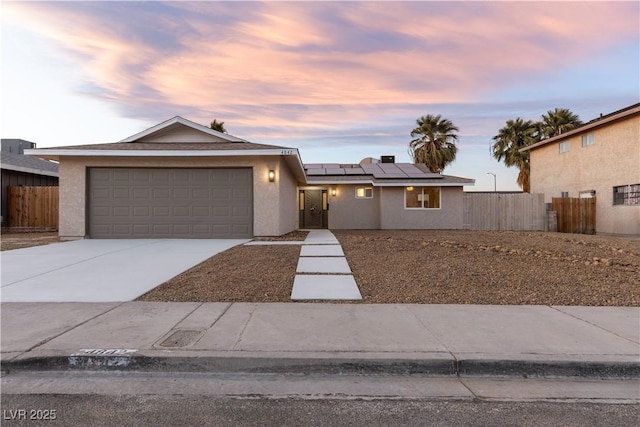 view of front of property with a garage, solar panels, driveway, and fence