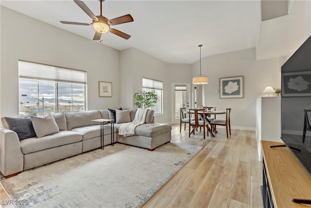 living area featuring a wealth of natural light, ceiling fan, light wood-type flooring, and baseboards