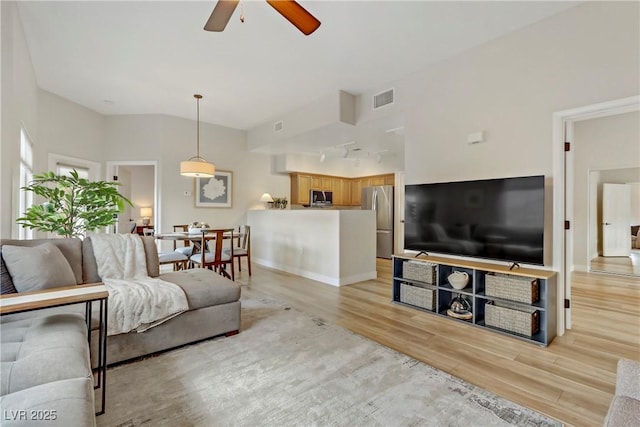 living room with light wood finished floors, visible vents, baseboards, and a ceiling fan