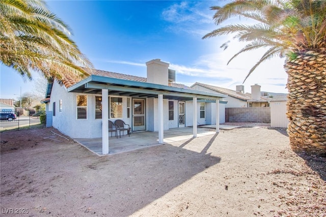 rear view of house featuring stucco siding, a patio, and fence