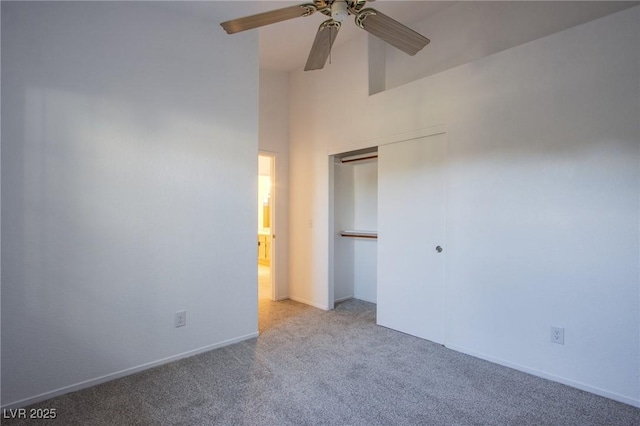 unfurnished bedroom with a ceiling fan, baseboards, a high ceiling, a closet, and carpet flooring