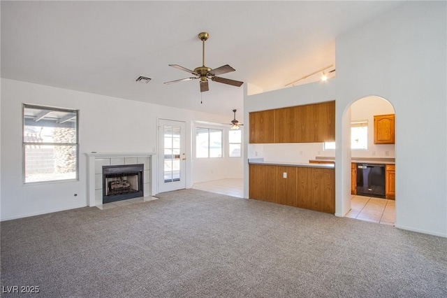 unfurnished living room with visible vents, light colored carpet, a ceiling fan, and a tile fireplace