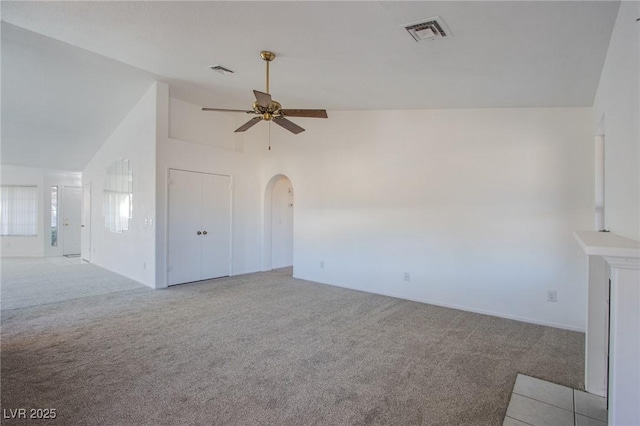 unfurnished living room featuring carpet flooring, arched walkways, visible vents, and ceiling fan