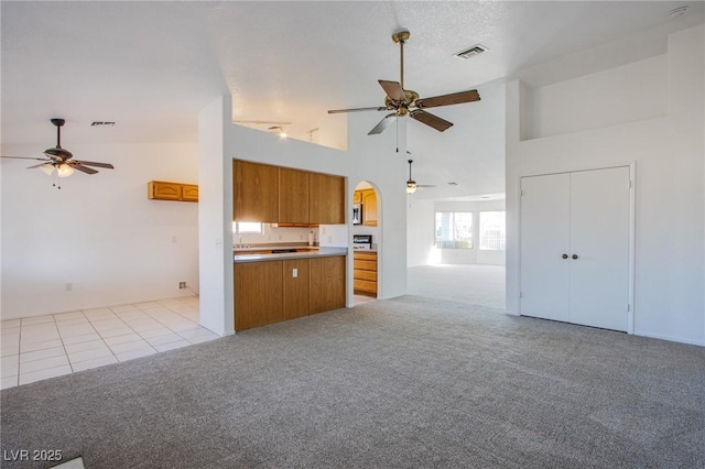 kitchen with visible vents, light colored carpet, open floor plan, and brown cabinetry