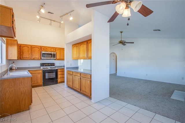 kitchen featuring visible vents, light carpet, a sink, stainless steel microwave, and range with gas stovetop