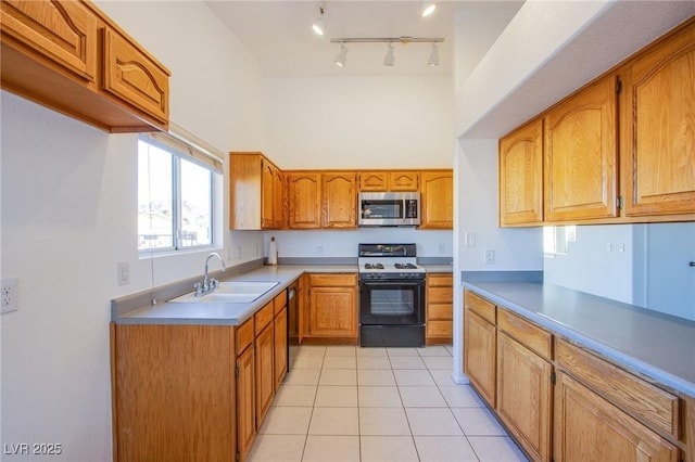 kitchen featuring light tile patterned floors, gas stove, a sink, stainless steel microwave, and brown cabinets