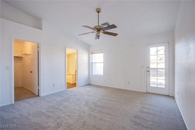 unfurnished bedroom with a walk in closet, lofted ceiling, carpet, and visible vents