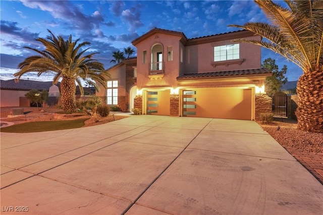 mediterranean / spanish house featuring a gate, an attached garage, stucco siding, concrete driveway, and a tile roof