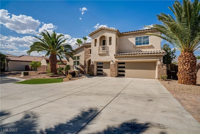 mediterranean / spanish house featuring stone siding, stucco siding, an attached garage, and driveway