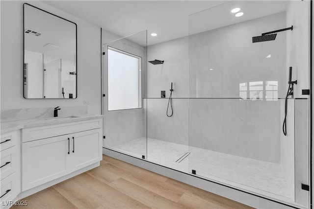 bathroom featuring vanity, wood finished floors, recessed lighting, and a walk in shower