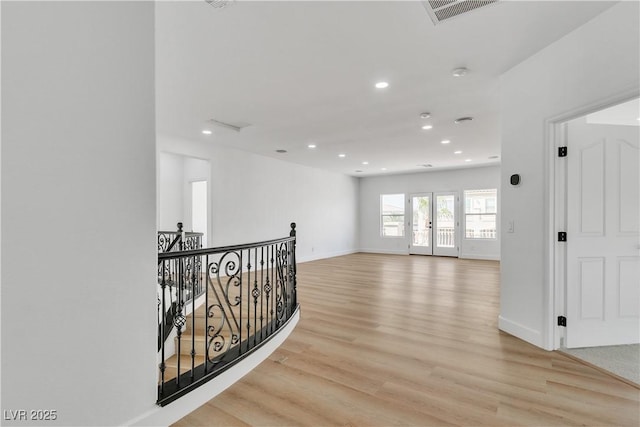 hallway featuring light wood-type flooring, visible vents, an upstairs landing, and recessed lighting