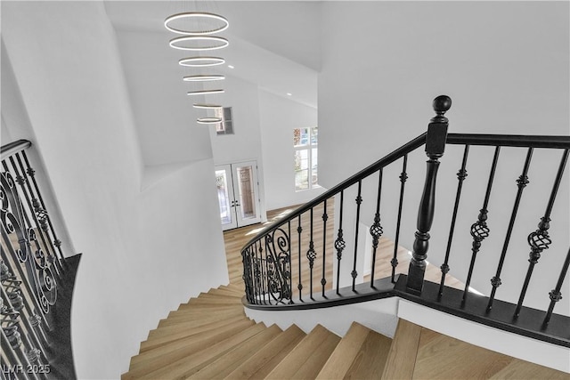 stairs featuring french doors, a high ceiling, and wood finished floors