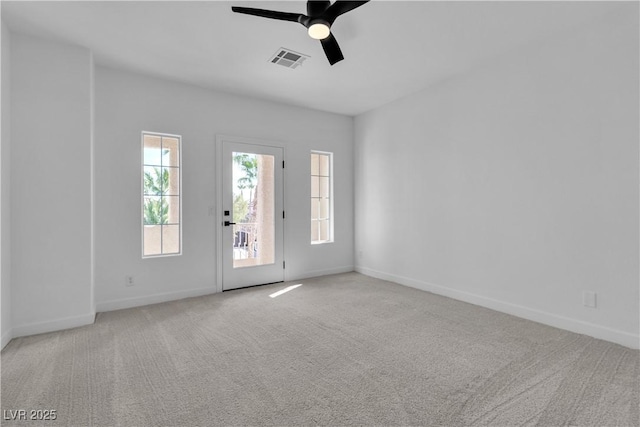 empty room with visible vents, baseboards, carpet, and a ceiling fan