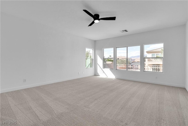 empty room with light carpet, visible vents, ceiling fan, and baseboards