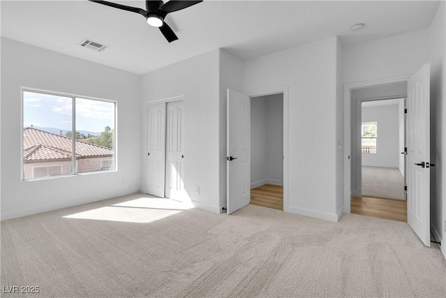 unfurnished bedroom featuring visible vents, carpet floors, and multiple windows