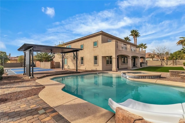 view of pool with a patio, a pool with connected hot tub, and fence