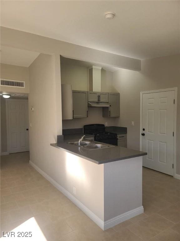 kitchen with a sink, visible vents, black gas range oven, and dark countertops