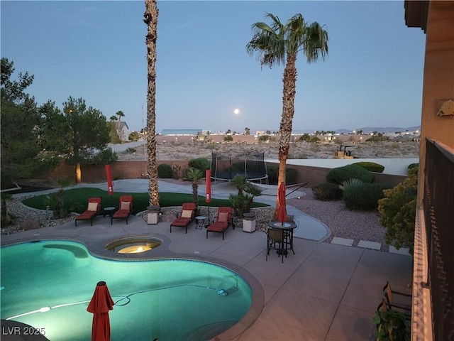 view of swimming pool featuring a trampoline, an in ground hot tub, and a patio area